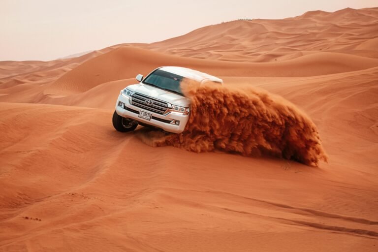 A Toyota Land Cruiser drives through the vast sandy dunes on an exciting off-road adventure.